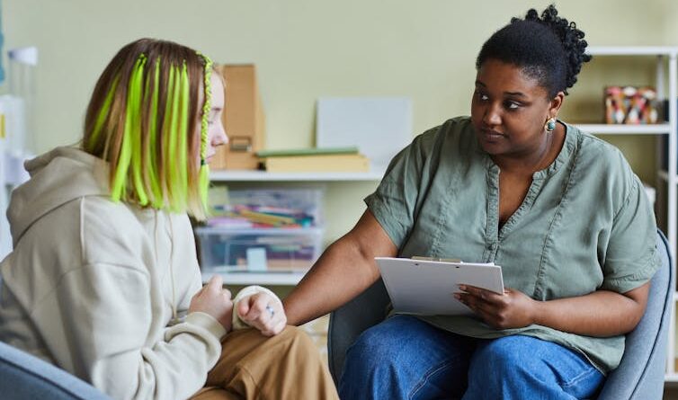 A school nurse comforts a young female patient.