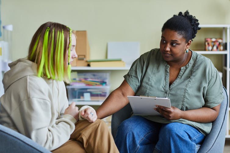 A school nurse comforts a young female patient.