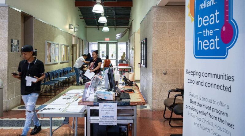 People walk in the hallway next to a table and a wall poster with a text about keeping the community cool.