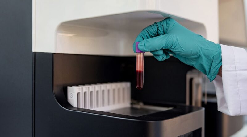 Lab technician takes a vial of blood.