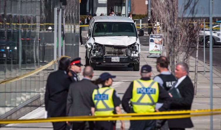 Police are standing on the side of the road in front of a damaged white van