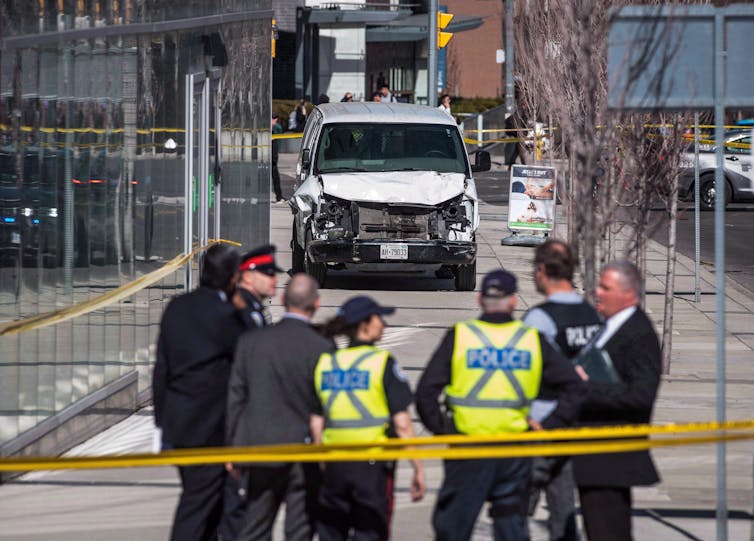 Police are standing on the side of the road in front of a damaged white van